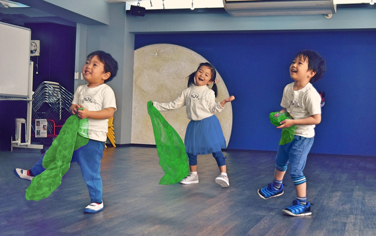 緑の布を持って笑顔で踊る子どもたち